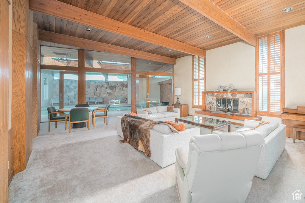 Carpeted living room with wood ceiling, a fireplace, floor to ceiling windows, and beam ceiling