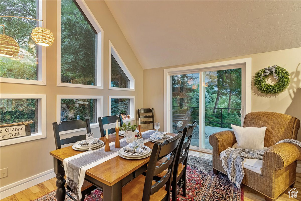 Dining space with light hardwood / wood-style floors, lofted ceiling, and a healthy amount of sunlight