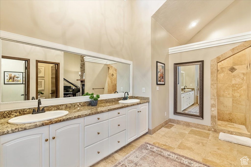 Bathroom with dual vanity, tile patterned floors, and high vaulted ceiling