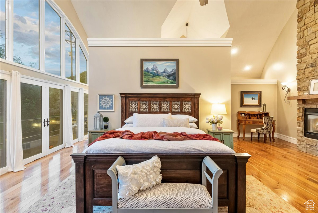 Bedroom featuring light wood-type flooring, a stone fireplace, and high vaulted ceiling