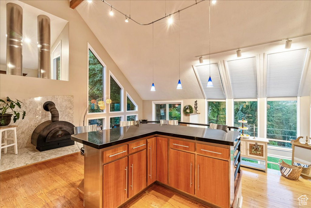 Kitchen featuring a wood stove, high vaulted ceiling, light wood-type flooring, and track lighting