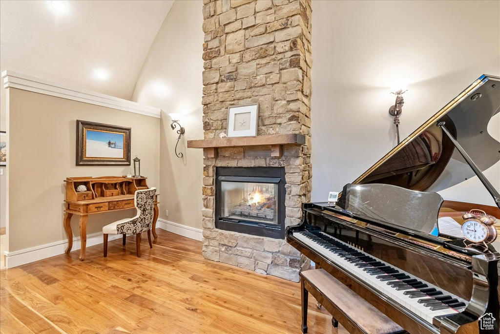 Living room featuring light hardwood / wood-style floors, a stone fireplace, and high vaulted ceiling