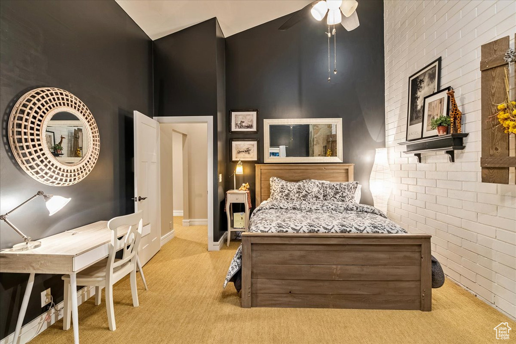 Carpeted bedroom featuring brick wall, ceiling fan, and a towering ceiling