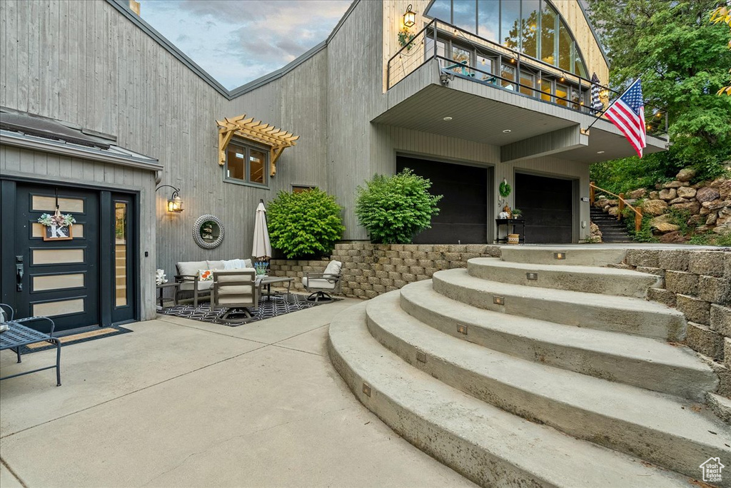 Exterior space with a garage, a balcony, a patio area, and outdoor lounge area