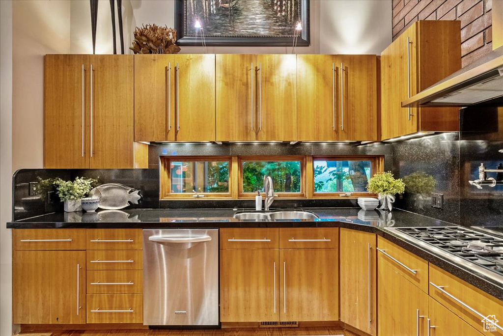 Kitchen with wall chimney range hood, sink, tasteful backsplash, and stainless steel appliances