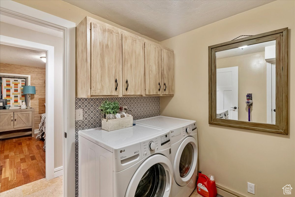 Washroom featuring cabinets, light hardwood / wood-style flooring, and washing machine and clothes dryer