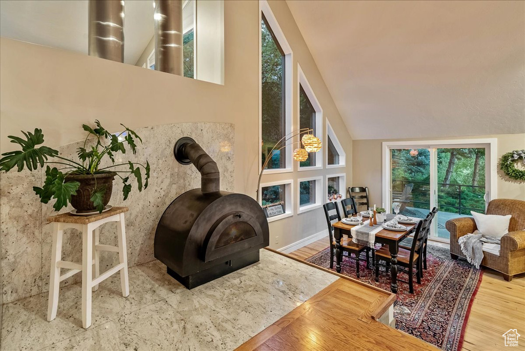 Living room with high vaulted ceiling, hardwood / wood-style floors, and a wood stove