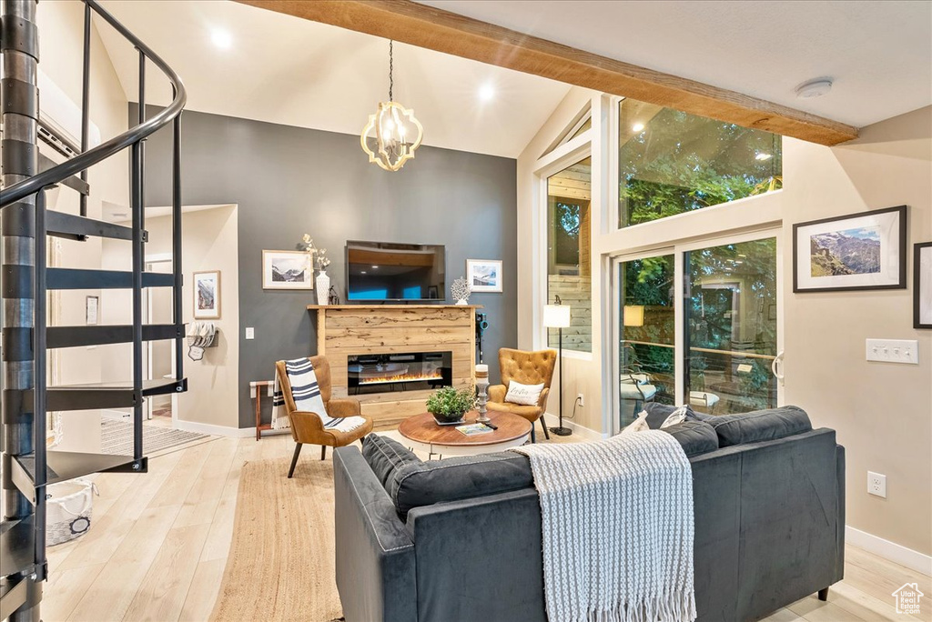 Living room featuring lofted ceiling with beams, a notable chandelier, and light hardwood / wood-style floors