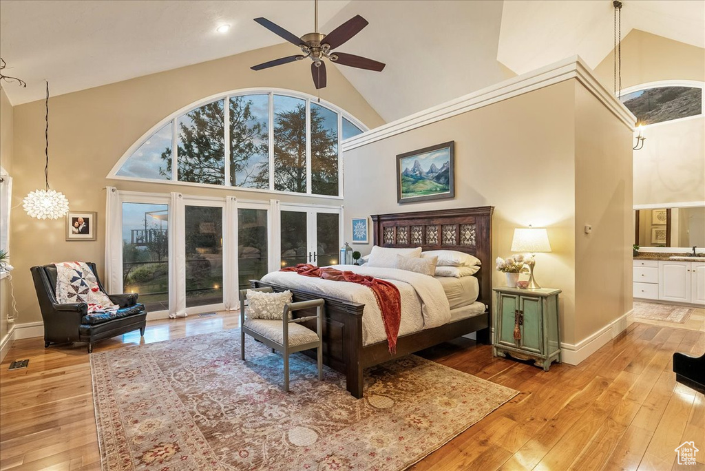 Bedroom with multiple windows, light wood-type flooring, and high vaulted ceiling