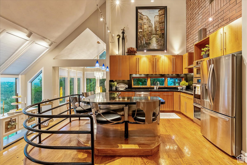 Kitchen with tasteful backsplash, stainless steel appliances, sink, pendant lighting, and light hardwood / wood-style floors