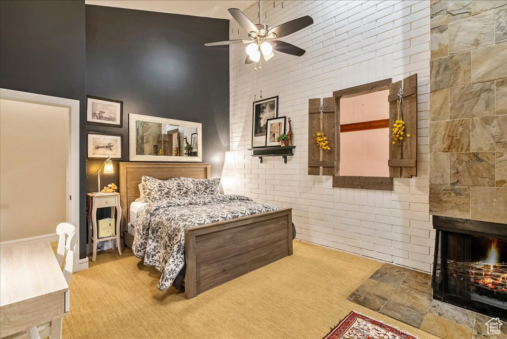 Carpeted bedroom with a high ceiling, a multi sided fireplace, and ceiling fan