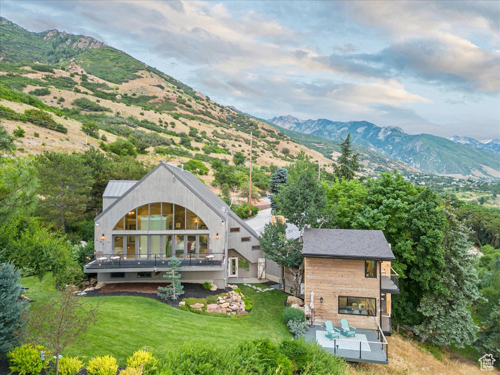 Exterior space featuring a mountain view, a patio, outdoor lounge area, and a lawn