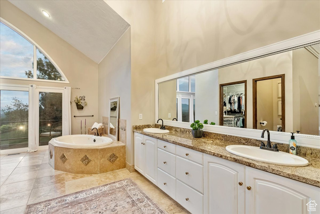 Bathroom with tile patterned floors, a washtub, high vaulted ceiling, and double vanity