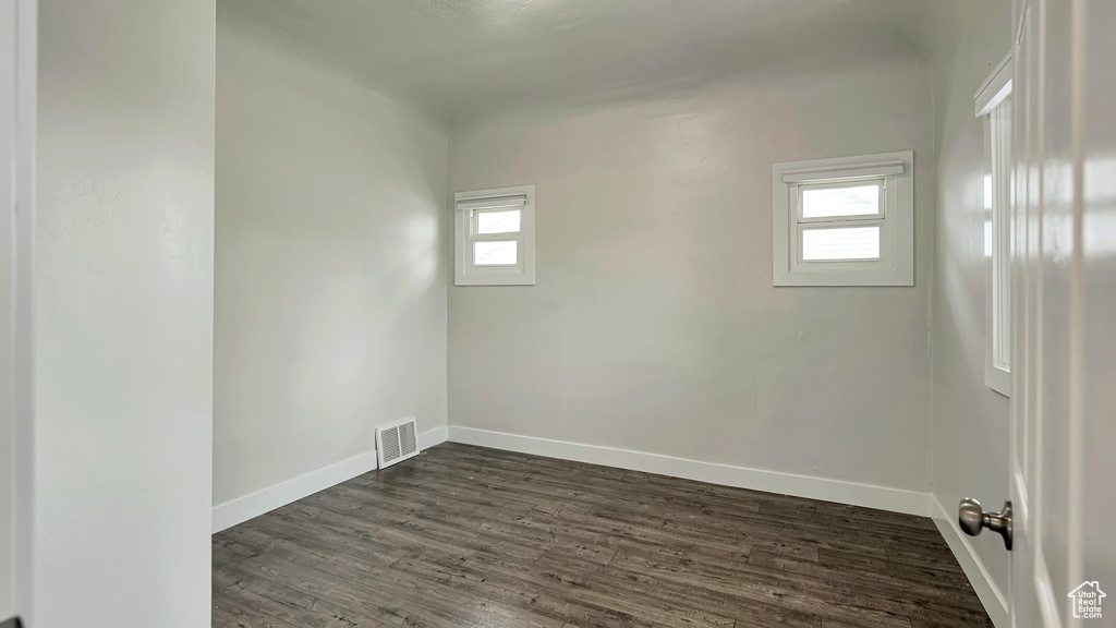 Unfurnished room featuring dark wood-type flooring and a healthy amount of sunlight