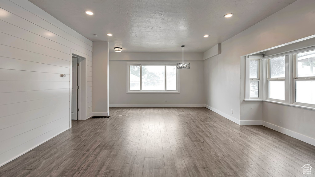 Spare room featuring hardwood / wood-style flooring, a notable chandelier, wooden walls, and a textured ceiling