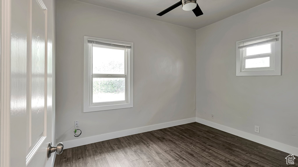 Empty room featuring dark hardwood / wood-style flooring and ceiling fan