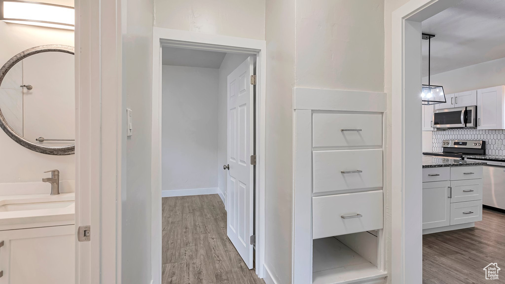 Corridor with light hardwood / wood-style floors and sink