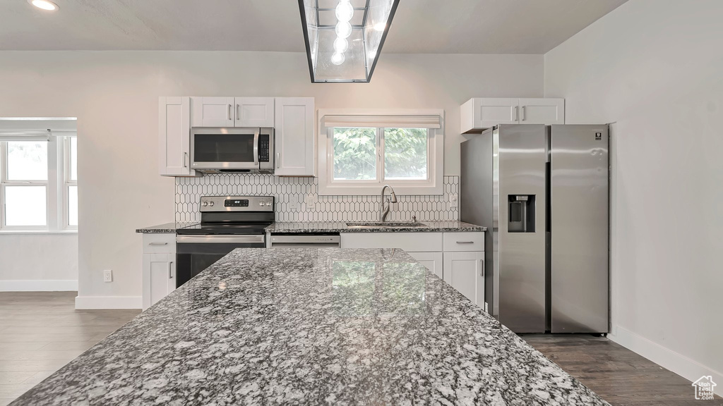 Kitchen featuring white cabinets, dark hardwood / wood-style flooring, stainless steel appliances, decorative backsplash, and sink