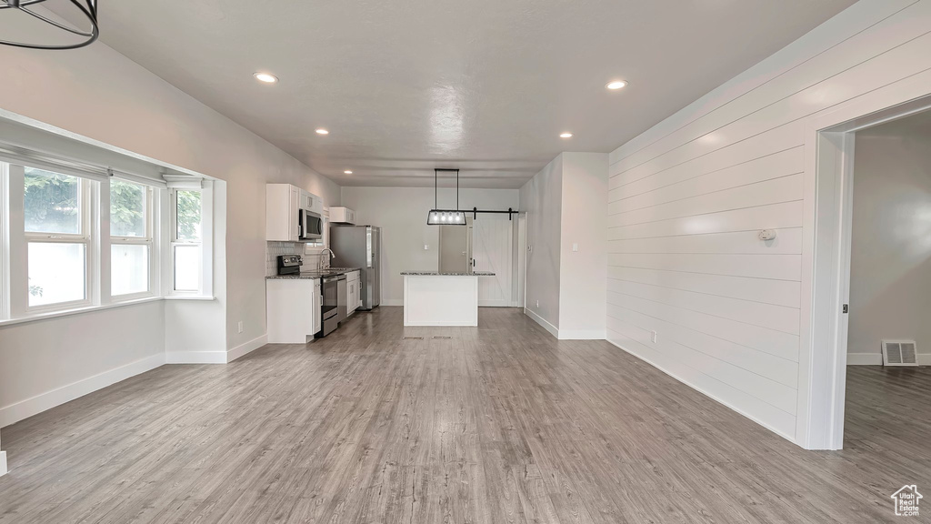 Unfurnished living room featuring a barn door and hardwood / wood-style flooring