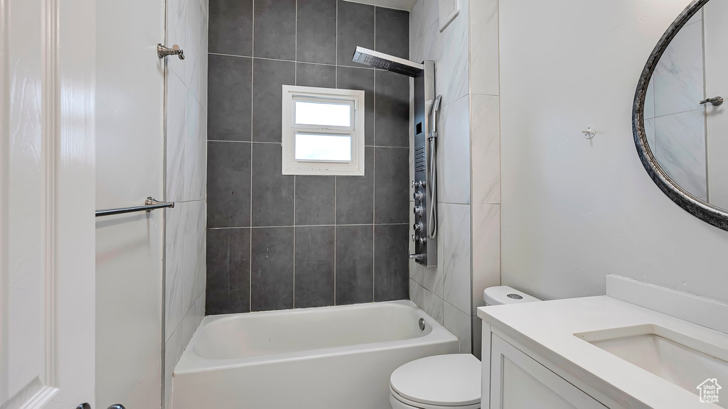 Full bathroom featuring vanity, tiled shower / bath combo, and toilet