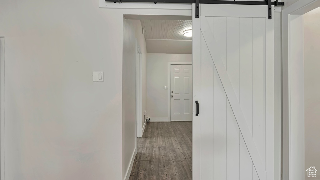 Hallway with a barn door and wood-type flooring