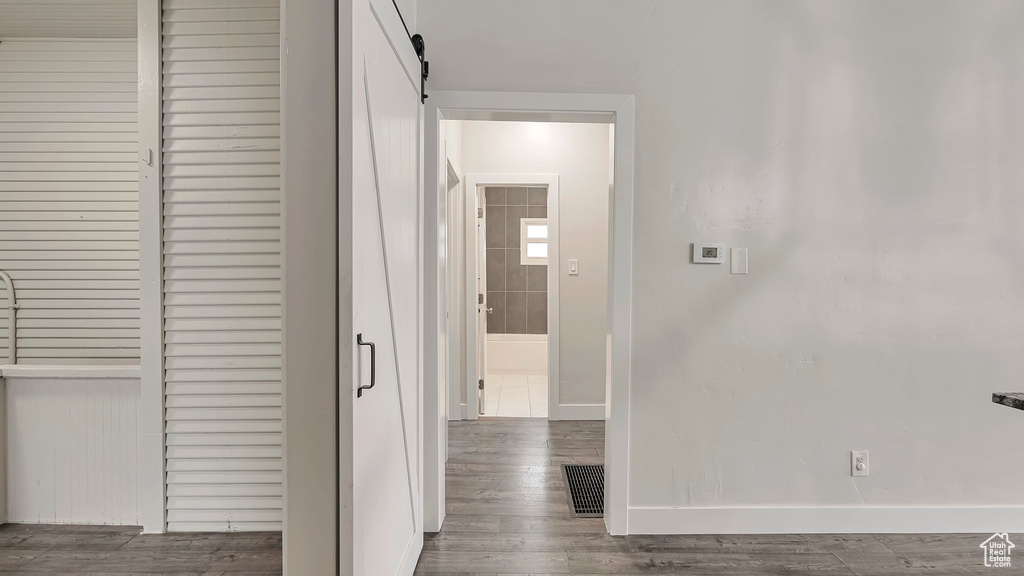 Hallway with wood-type flooring and a barn door