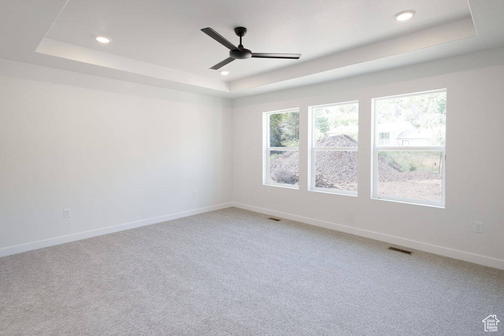 Unfurnished room featuring a tray ceiling, ceiling fan, and carpet