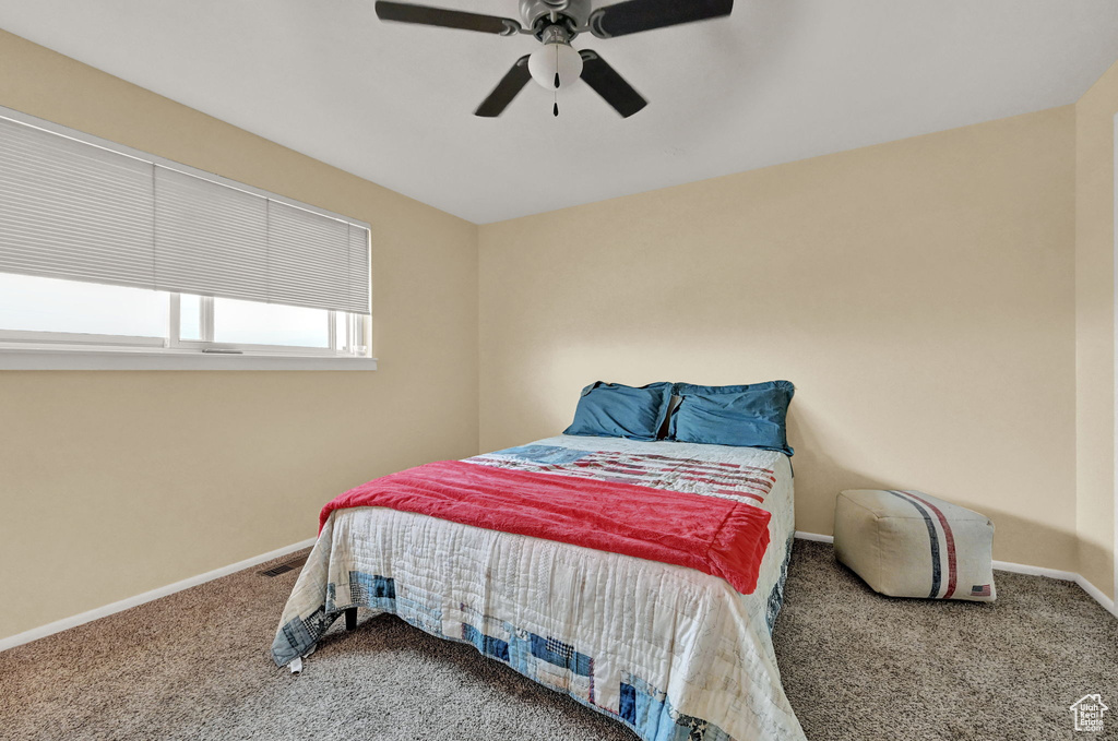 Carpeted bedroom featuring ceiling fan