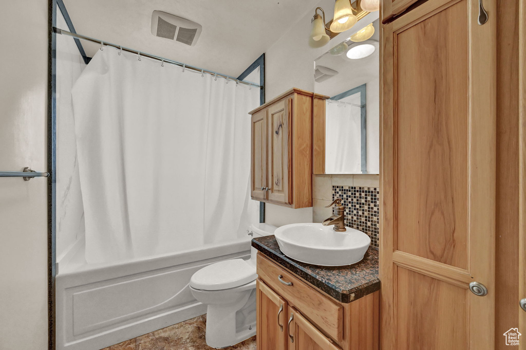 Full bathroom with vanity, shower / bath combo with shower curtain, toilet, tile patterned flooring, and backsplash