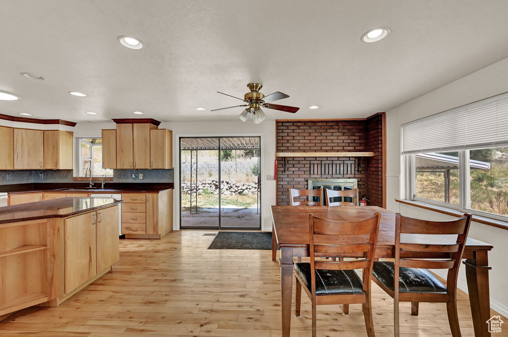 Kitchen featuring brick wall, ceiling fan, backsplash, and light hardwood / wood-style floors