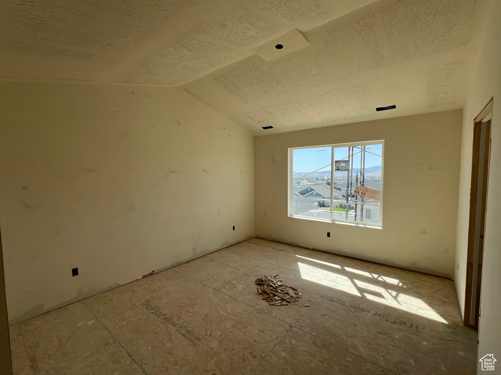 Empty room with vaulted ceiling and a textured ceiling