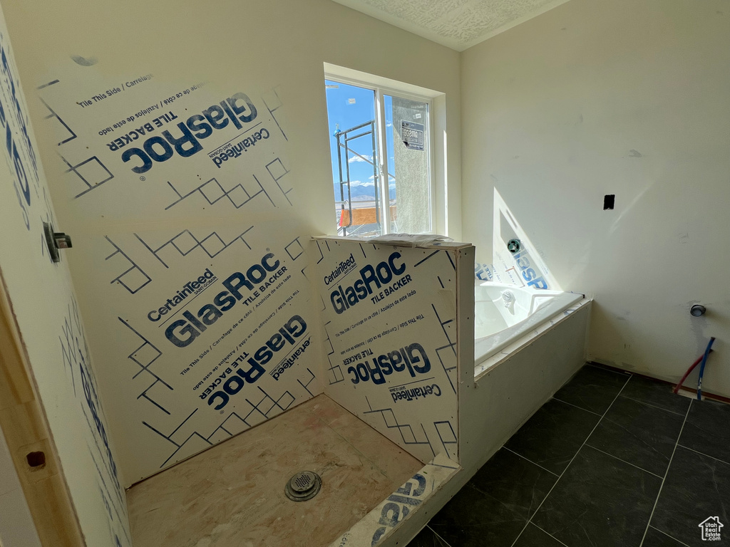 Bathroom featuring a bath, a textured ceiling, and tile patterned flooring