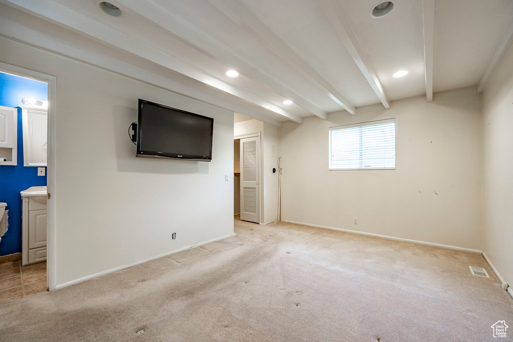 Interior space featuring light colored carpet and beam ceiling