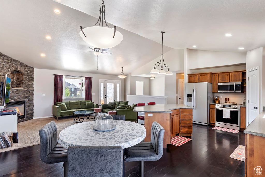 Dining room with high vaulted ceiling, a fireplace, ceiling fan, and dark hardwood / wood-style floors