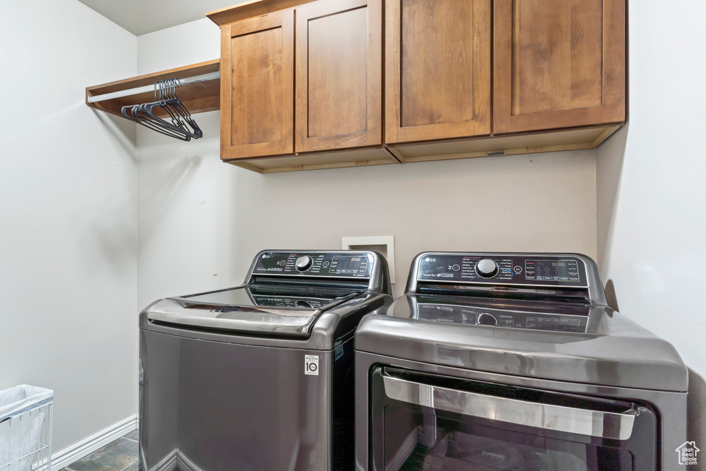 Washroom featuring washing machine and clothes dryer, tile patterned flooring, and cabinets