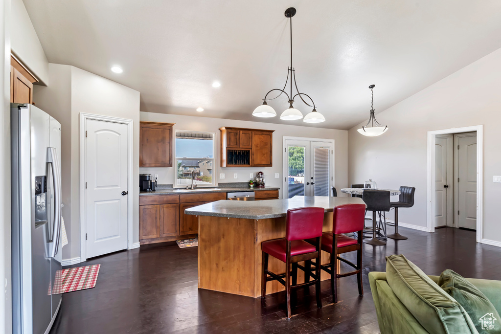 Kitchen with lofted ceiling, a breakfast bar area, dark hardwood / wood-style flooring, appliances with stainless steel finishes, and decorative light fixtures