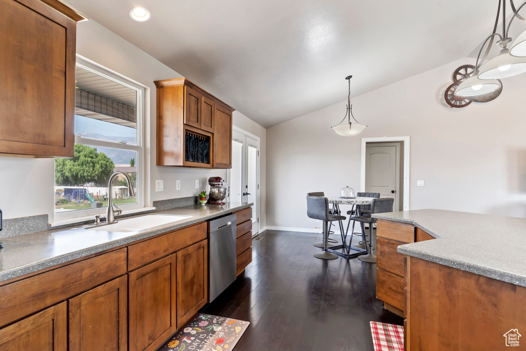 Kitchen featuring dishwasher, dark hardwood / wood-style flooring, hanging light fixtures, vaulted ceiling, and sink