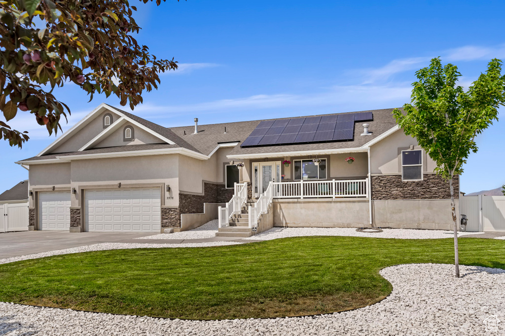 Ranch-style house with a garage, a front lawn, and solar panels