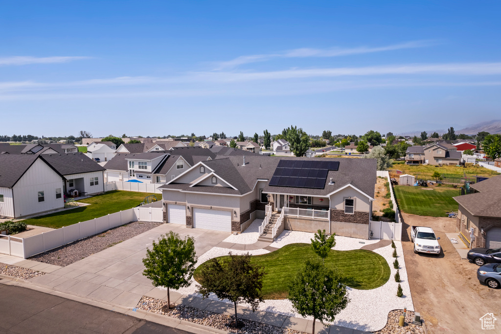 View of front of home featuring a garage, solar panels, and a front lawn