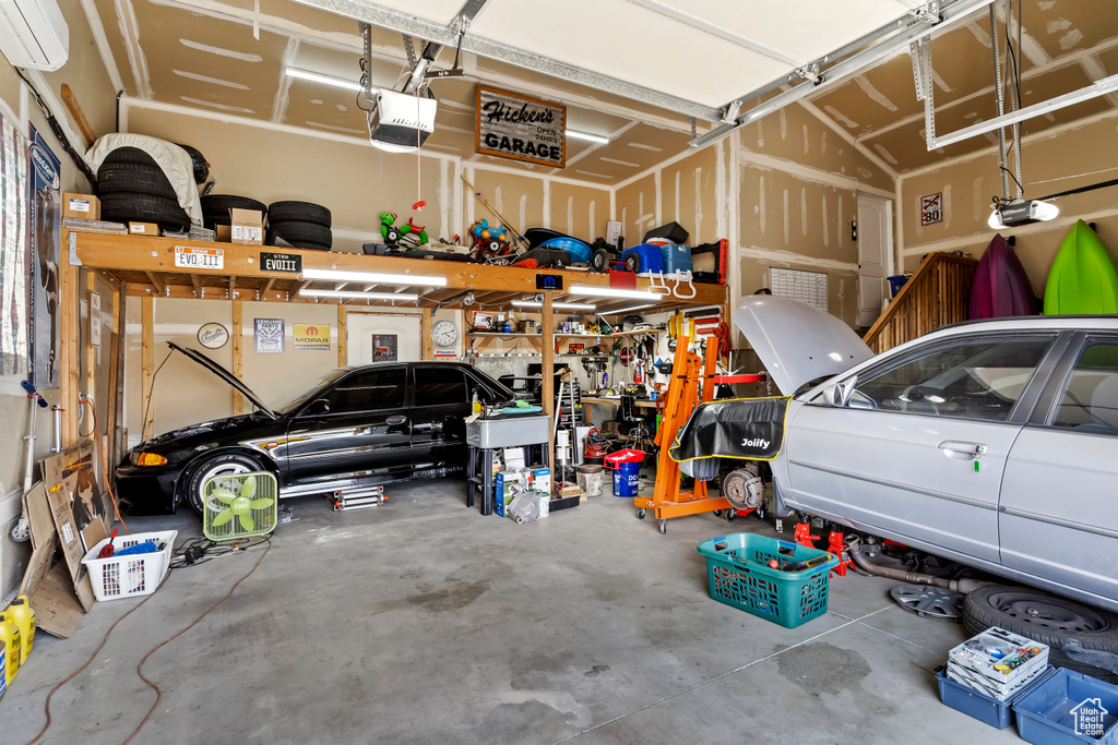 Garage with a workshop area, an AC wall unit, and a garage door opener