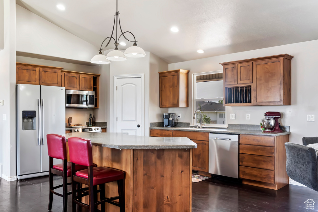 Kitchen featuring lofted ceiling, a breakfast bar, a center island, dark hardwood / wood-style floors, and appliances with stainless steel finishes