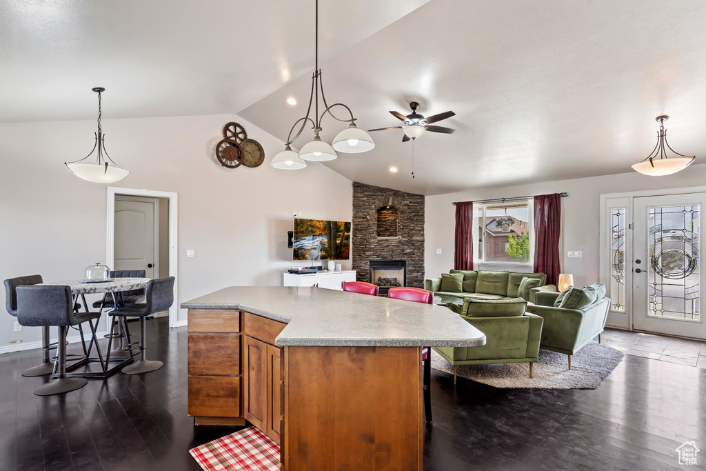 Kitchen with a fireplace, ceiling fan, hanging light fixtures, dark hardwood / wood-style flooring, and a kitchen island