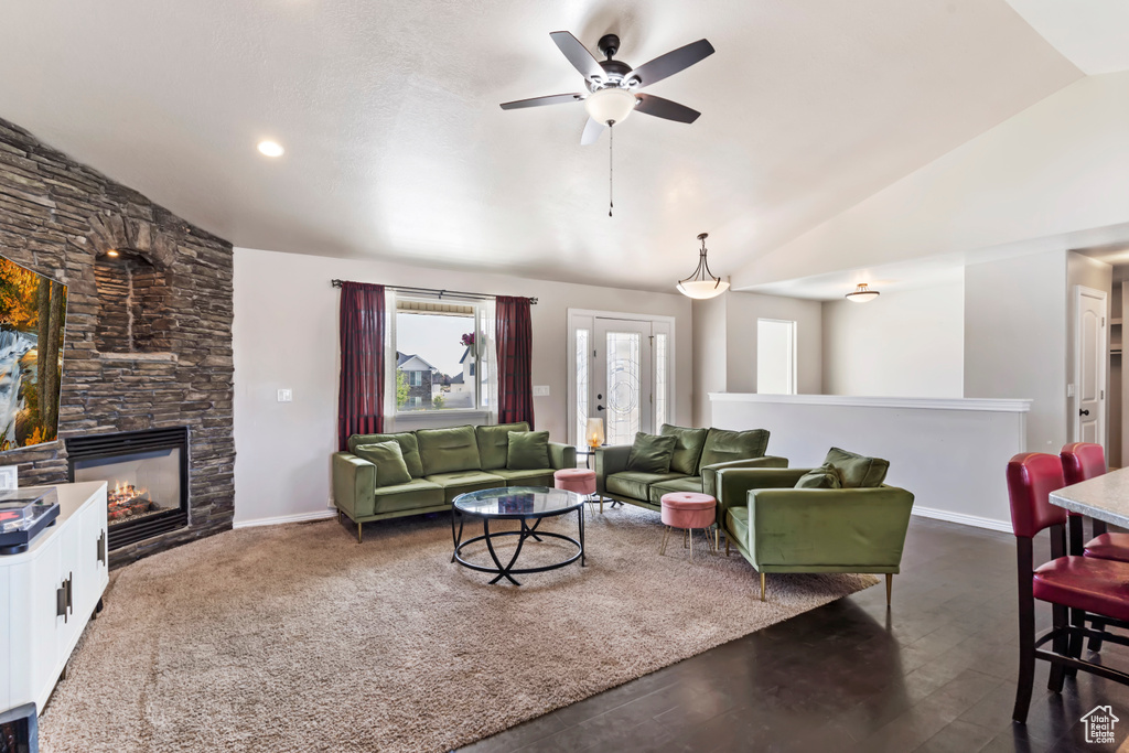 Living room featuring a fireplace, ceiling fan, and vaulted ceiling