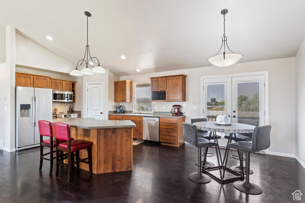 Kitchen featuring hanging light fixtures, dark hardwood / wood-style flooring, a center island, appliances with stainless steel finishes, and lofted ceiling