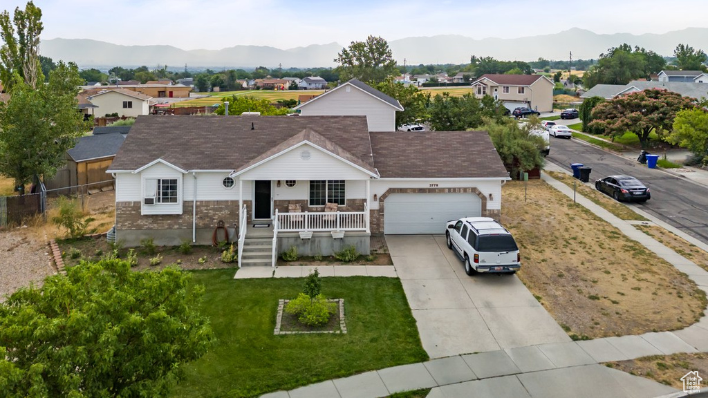 Ranch-style home featuring a mountain view, covered porch, and a garage