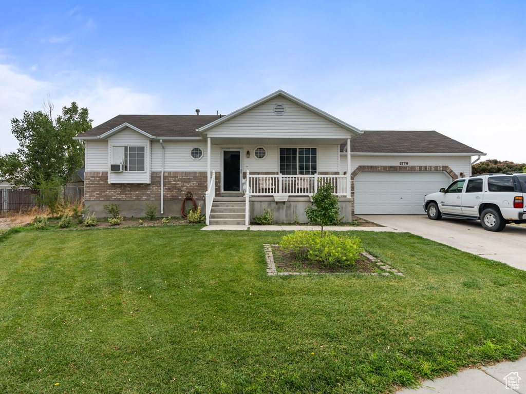 Ranch-style house featuring covered porch, a garage, and a front lawn