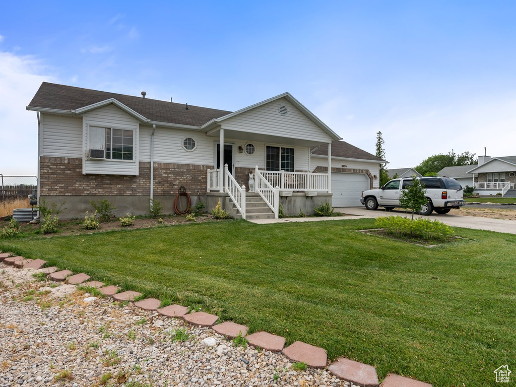 Single story home featuring a porch, a garage, and a front yard