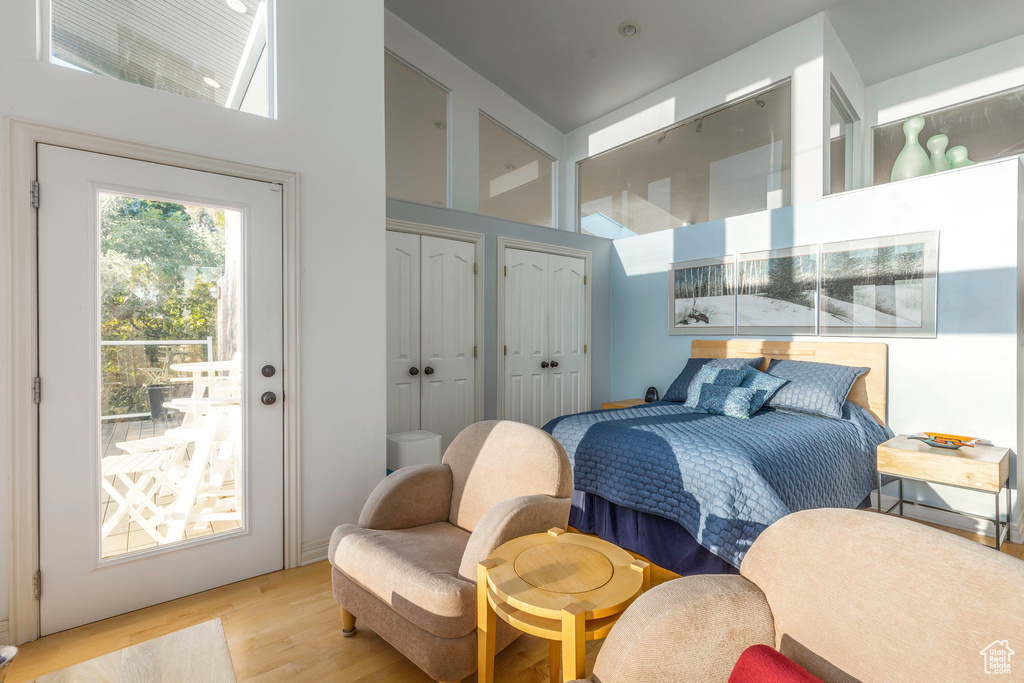 Bedroom with two closets, light hardwood / wood-style flooring, and a towering ceiling