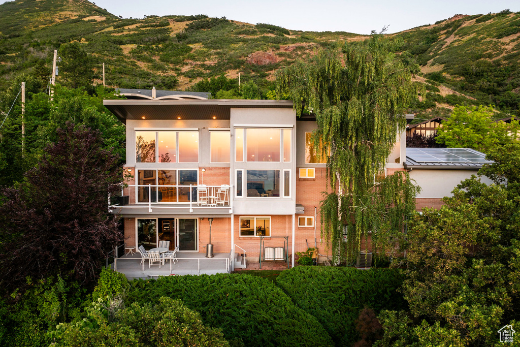 Rear view of property with a mountain view, a patio area, a balcony, and cooling unit