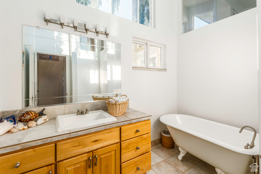 Bathroom featuring vanity, tile patterned flooring, a bathing tub, and a wealth of natural light